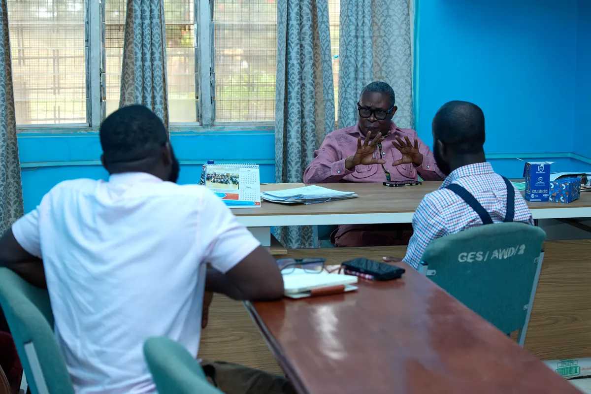 Three people seated around a conference table in discussion.